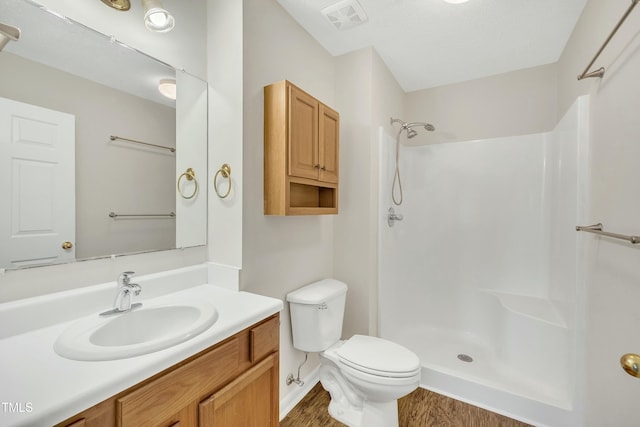 bathroom featuring walk in shower, vanity, wood-type flooring, and toilet