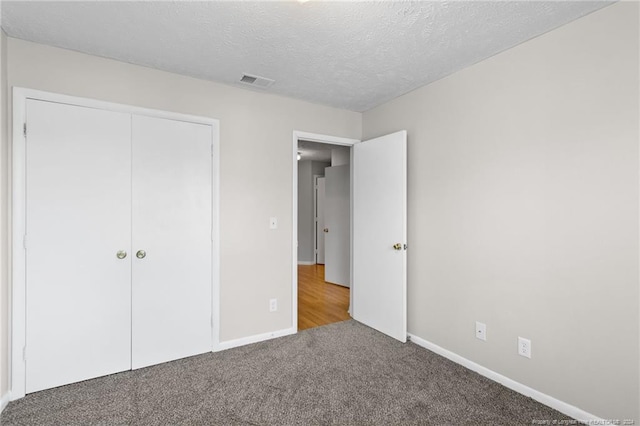 unfurnished bedroom with a textured ceiling, carpet floors, and a closet