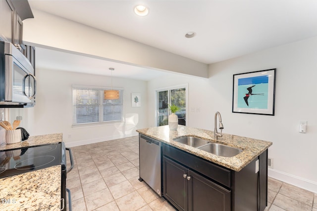 kitchen with a kitchen island with sink, sink, light stone countertops, decorative light fixtures, and stainless steel appliances