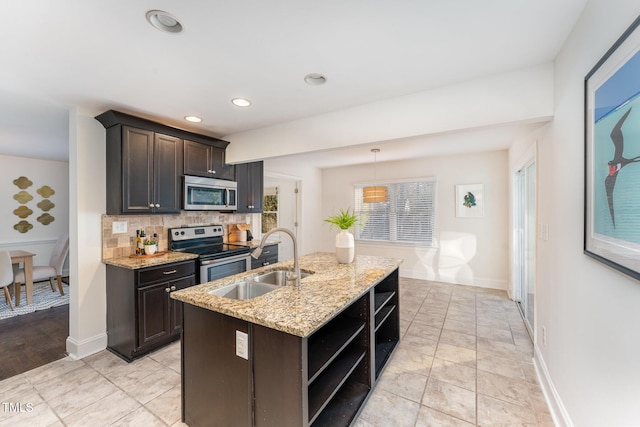 kitchen with pendant lighting, a center island with sink, sink, dark brown cabinetry, and stainless steel appliances