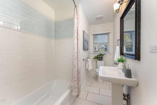 bathroom featuring toilet and shower / tub combo with curtain