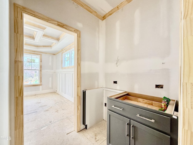 interior space with ornamental molding, coffered ceiling, and a decorative wall