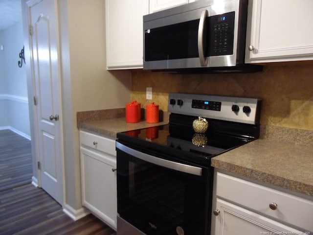 kitchen featuring stainless steel appliances, dark wood-type flooring, white cabinets, and backsplash