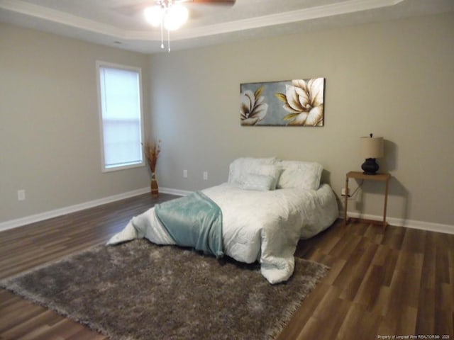 bedroom with ceiling fan, a tray ceiling, and dark hardwood / wood-style flooring