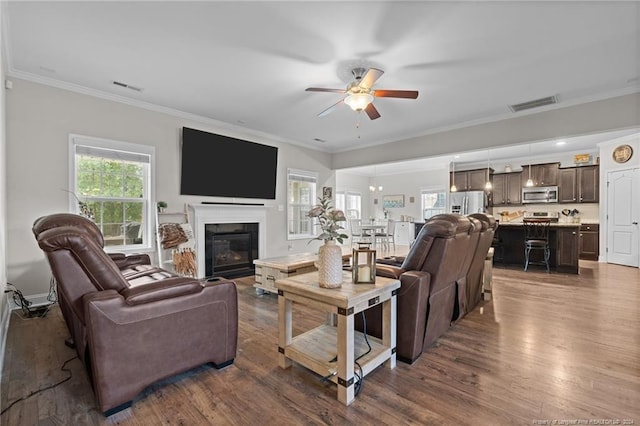 living room with crown molding, ceiling fan, and dark wood-type flooring