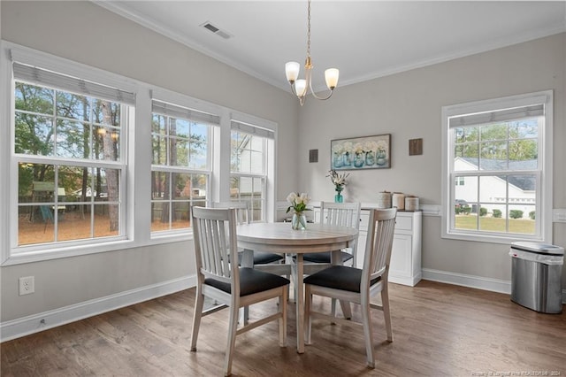 dining space featuring hardwood / wood-style floors, a notable chandelier, and ornamental molding