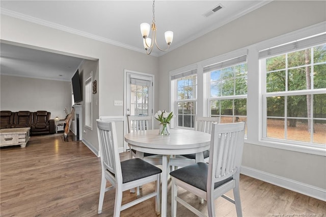 dining room with a chandelier, wood-type flooring, a wealth of natural light, and crown molding