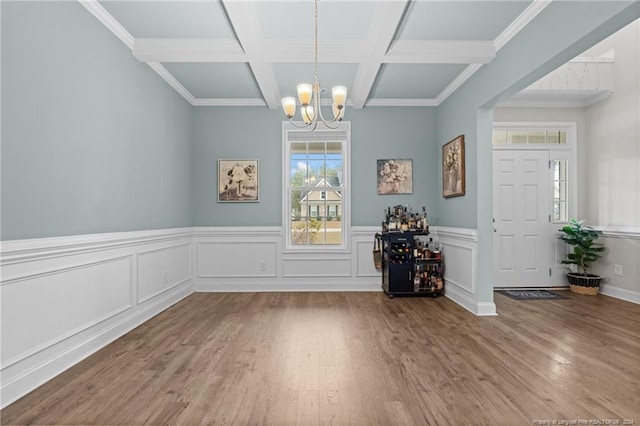 unfurnished dining area featuring an inviting chandelier, coffered ceiling, hardwood / wood-style flooring, ornamental molding, and beamed ceiling