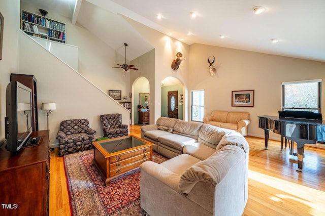 living room with ceiling fan, high vaulted ceiling, and light wood-type flooring