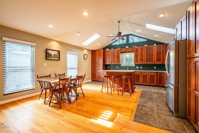 kitchen with stainless steel fridge, a breakfast bar, a healthy amount of sunlight, and a center island