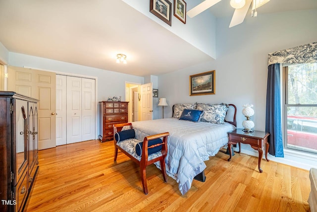 bedroom featuring ceiling fan, light hardwood / wood-style floors, lofted ceiling, and a closet