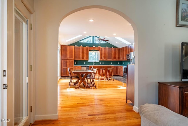 kitchen with appliances with stainless steel finishes, light hardwood / wood-style flooring, ceiling fan, and lofted ceiling