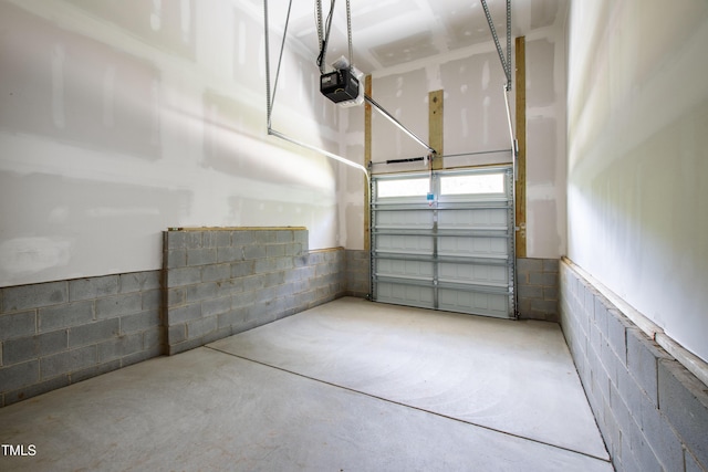 garage featuring concrete block wall and a garage door opener