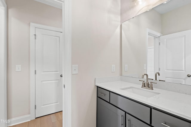 bathroom featuring baseboards, wood finished floors, and vanity