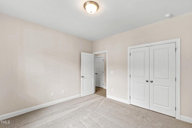 unfurnished bedroom with a closet, baseboards, and carpet flooring