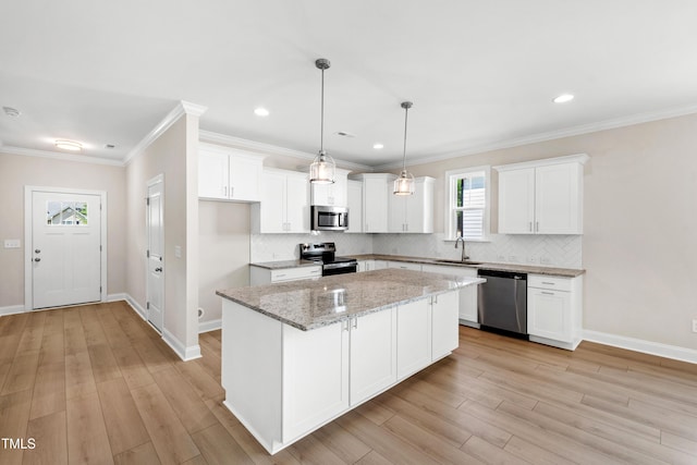kitchen with a sink, appliances with stainless steel finishes, tasteful backsplash, and a kitchen island
