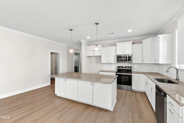 kitchen with appliances with stainless steel finishes, a sink, a center island, decorative backsplash, and light wood-type flooring