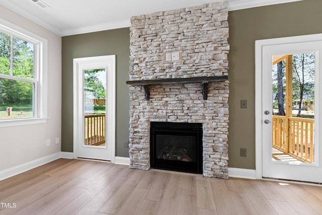 unfurnished living room featuring plenty of natural light, crown molding, wood finished floors, and a fireplace