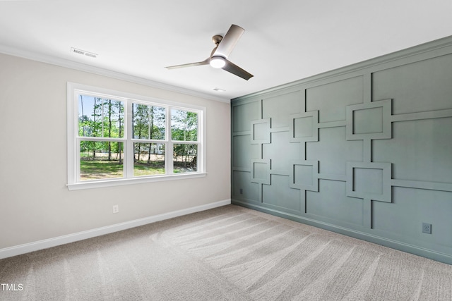 spare room with visible vents, crown molding, baseboards, light colored carpet, and a ceiling fan