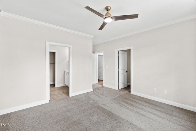 unfurnished bedroom featuring crown molding, baseboards, carpet, and a walk in closet