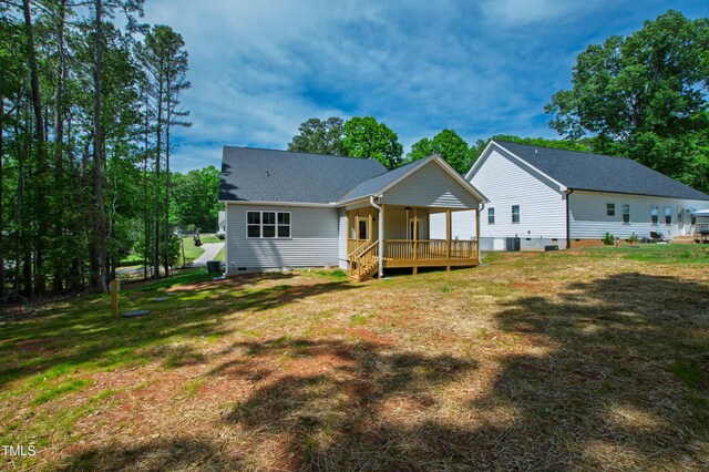 back of house with a porch, roof with shingles, a yard, and crawl space