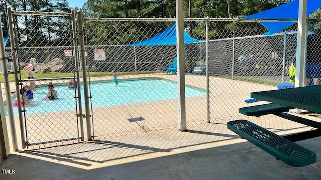 view of swimming pool featuring fence and a gate