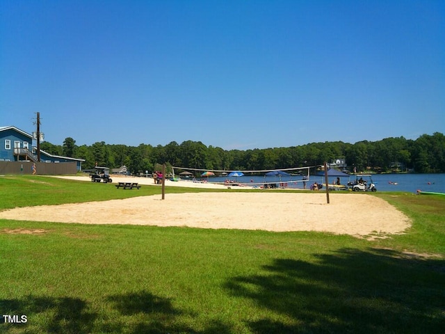view of property's community featuring a lawn, a forest view, and volleyball court