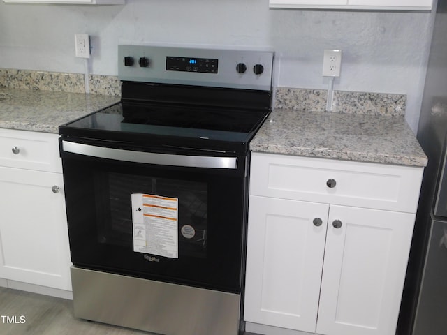 kitchen with white cabinetry, light stone counters, stainless steel electric range oven, and light hardwood / wood-style flooring