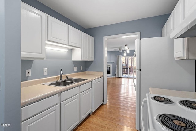 kitchen featuring white appliances, sink, light hardwood / wood-style flooring, ceiling fan, and white cabinetry