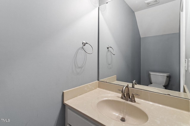 bathroom featuring vanity, toilet, and lofted ceiling