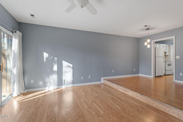 unfurnished living room featuring ceiling fan with notable chandelier and light wood-type flooring