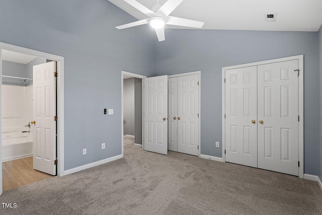 unfurnished bedroom with light carpet, connected bathroom, two closets, and ceiling fan