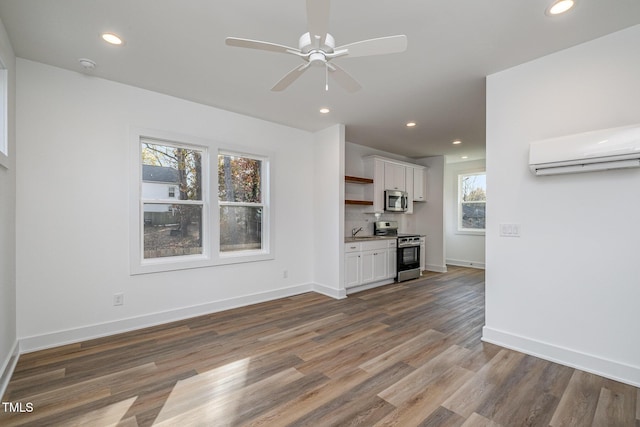 unfurnished living room with a wall mounted AC, dark hardwood / wood-style flooring, and a healthy amount of sunlight