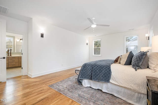 bedroom featuring light wood-type flooring, ensuite bath, and ceiling fan