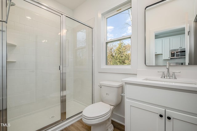 bathroom featuring vanity, hardwood / wood-style flooring, toilet, and a shower with shower door