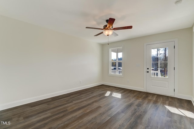 spare room featuring dark hardwood / wood-style floors, ceiling fan, and a healthy amount of sunlight