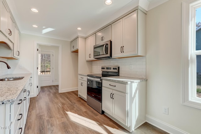 kitchen with light stone countertops, appliances with stainless steel finishes, sink, light hardwood / wood-style flooring, and white cabinets