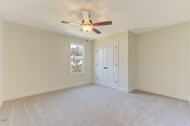 unfurnished bedroom featuring ceiling fan, a closet, and light carpet