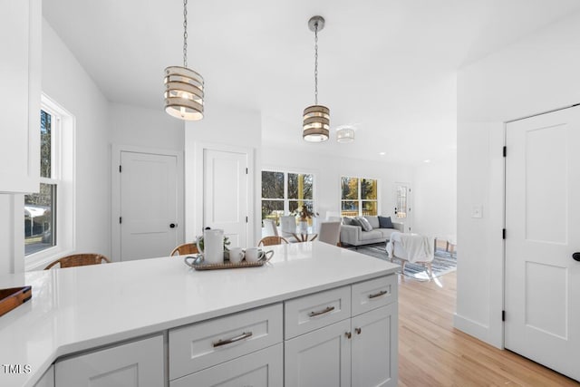 kitchen with a notable chandelier, light wood-type flooring, hanging light fixtures, and a wealth of natural light