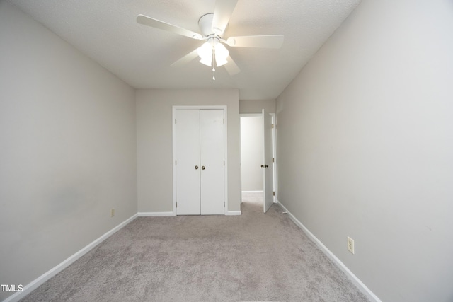 unfurnished bedroom with ceiling fan, a closet, light colored carpet, and a textured ceiling