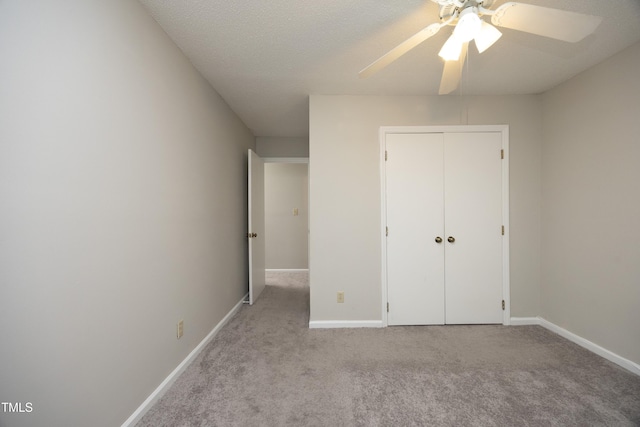 unfurnished bedroom featuring ceiling fan, a closet, light carpet, and a textured ceiling