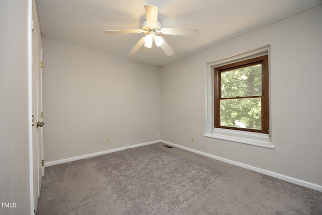 carpeted spare room featuring a textured ceiling and ceiling fan