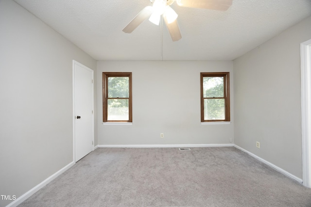 carpeted spare room featuring ceiling fan, plenty of natural light, and a textured ceiling