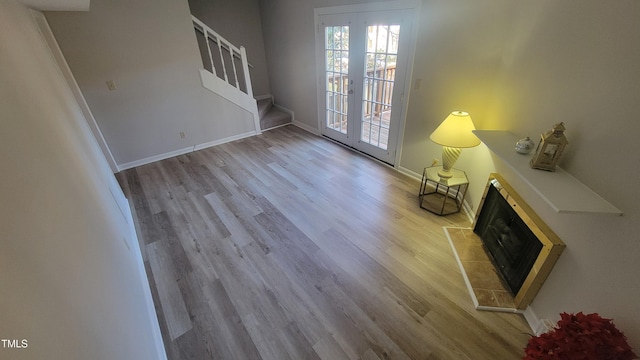 unfurnished living room with french doors, light hardwood / wood-style flooring, and a tiled fireplace