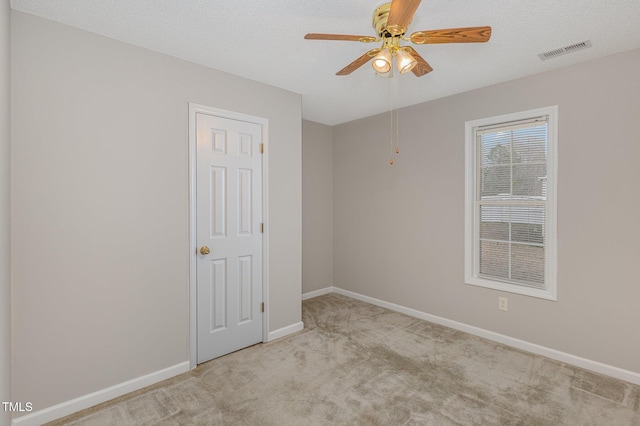 carpeted spare room with ceiling fan and a textured ceiling