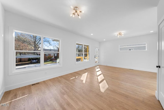 unfurnished living room featuring a notable chandelier and light wood-type flooring