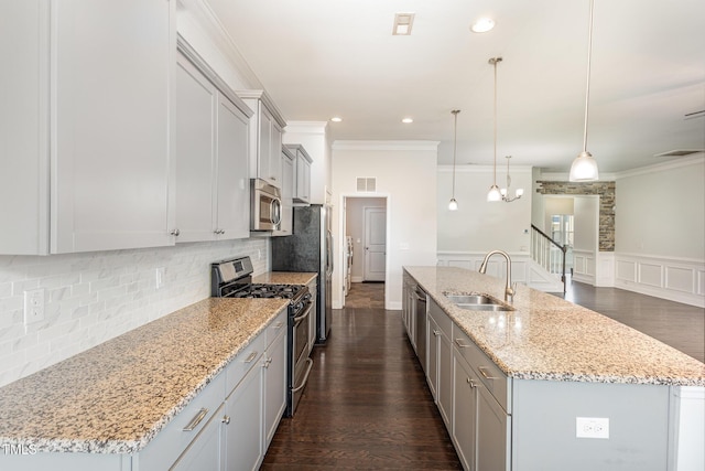 kitchen featuring a kitchen island with sink, sink, pendant lighting, and appliances with stainless steel finishes