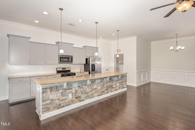 kitchen featuring appliances with stainless steel finishes, a center island with sink, light stone counters, and dark wood-type flooring