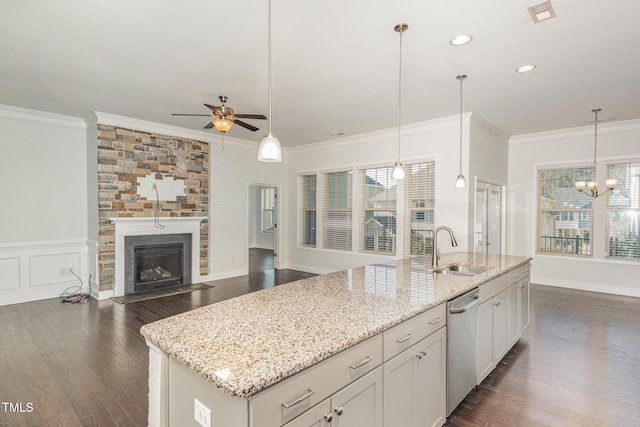 kitchen featuring a center island with sink, a stone fireplace, sink, stainless steel dishwasher, and dark hardwood / wood-style flooring