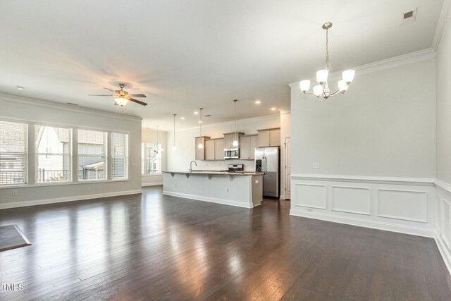 unfurnished living room with visible vents, ornamental molding, dark wood-style flooring, and ceiling fan with notable chandelier